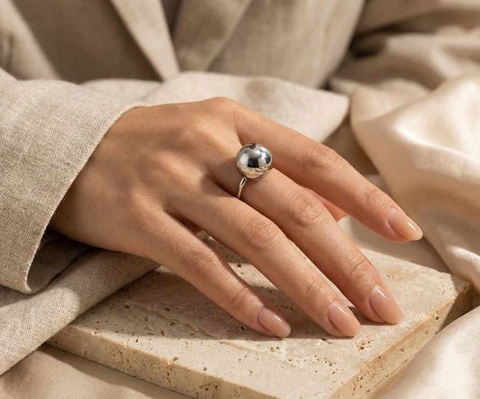 Main portant une bague en acier inoxydable argenté en forme de boule pour femme